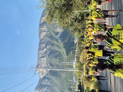 Menschen in bunten Trikots bei einer Laufveranstaltung auf einer Straße, im Hintergrund ist ein Bergrelief zu sehen.