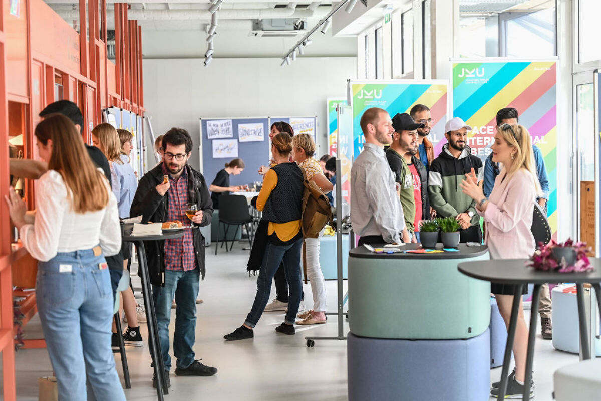Einige Leute, die sich am Tag der offenen Tür in unterschiedlichen Grüppchen unterhalten. 