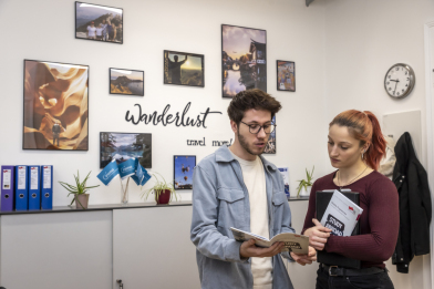 Zwei Personen unterhalten sich, im Hintergrund sieht man Fotos von Auslandsaufenthalten