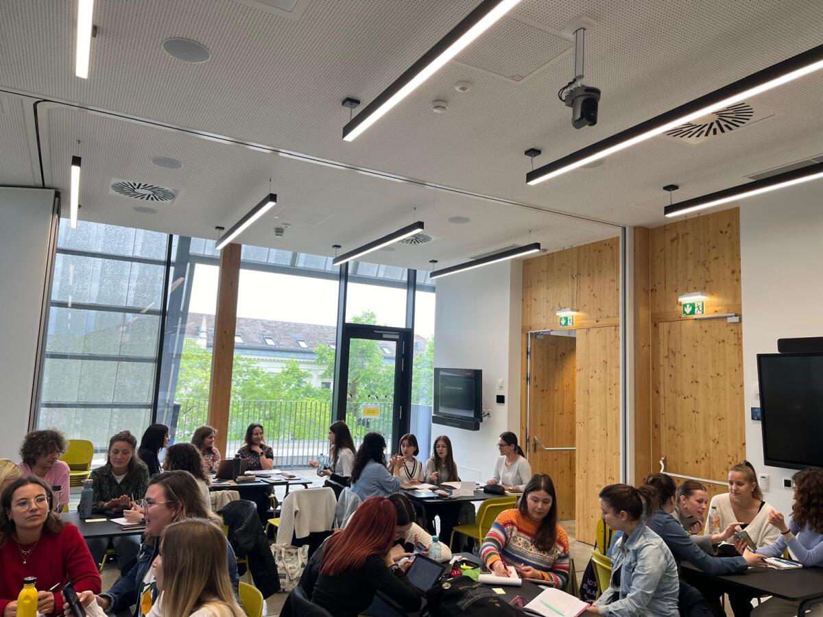 Studierende sitzen an Tischen und machen Gruppenarbeiten